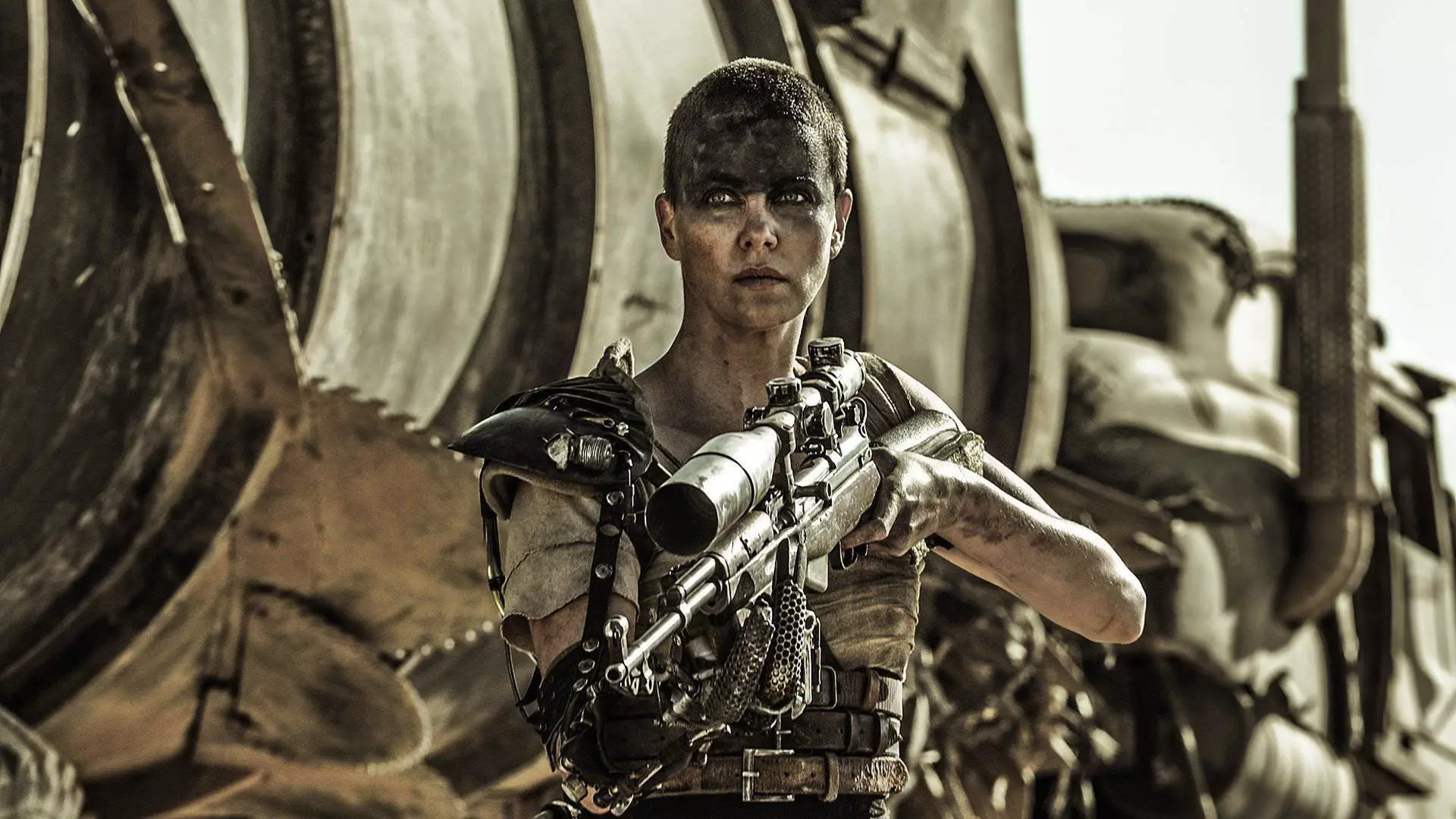 شارلیز ترون در نقش فیوروسا با اسنایپری در دست در کنار تانکر آب در فیلم Mad Max: Fury Road